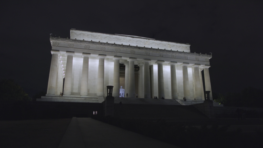 Tourists visit the Lincoln Memorial in Washington, D.C. at night. Wide shot from the east side of the building