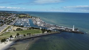 St Kilda Marina wide shot aerial showing the light house and the coastline along St Kilda Beach and Port Phillip Bay on a sunny day. Drone video from Melbourne, Victoria, Australia