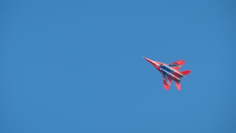 NIZHNY NOVGOROD, RUSSIA - AUGUST 14, 2021: Air Show. Military aircraft Mig 29 flying in blue sky and doing stunts - slow motion. Performance, extreme, aerobatic and sport concept