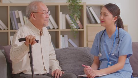 Asian woman doctor talking and laughing with senior or elderly man and nursing at home.Happy elderly enjoy cheerful with doctor or nurse on couch.smiling caregiver woman visit senior patient at home