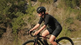 Cyclist on bicycle. Female athlete speeding downhill from mountain hill. Professional road cyclist training on bike, doing hard workout exercises. Woman cycling outdoors. Cycling and triathlon
