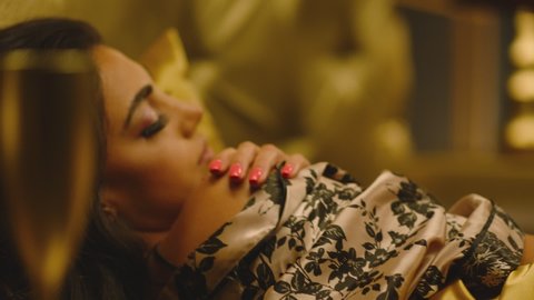 Beautiful Young Woman Sleeping Dreaming and Flirting in Bed . Female model resting lying asleep inside luxury golden bedroom . Golden room in hotel , house . Shot on ARRI cinema camera in slow motion