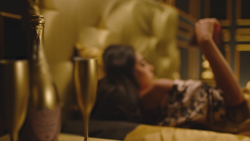 Beautiful Young Woman Sleeping Dreaming and Flirting in Bed . Female model resting lying asleep inside luxury golden bedroom . Golden room in hotel , house . Shot on ARRI cinema camera in slow motion