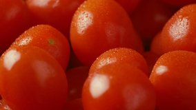 Fresh Ferdinand type Spanish Cherry Tomatoes covered with water drops. Close up video. Rotating slowly.