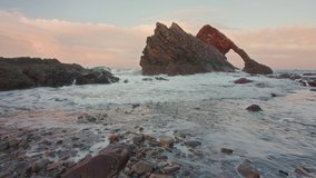 Real time footage of natural sea arch with sea movement. This is famous rock formation on the Moray Coast, Scottish Highlands, Scotland. Bow Fiddle Rock at sunset, no people.