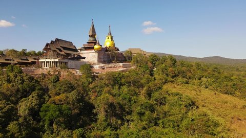 Aerial reverse footage from an angle and lower altitude revealing the Wat Somdet Phu Ruea and the beautiful landscape plus the blue sky, Ming Mueang, Loei in Thailand.