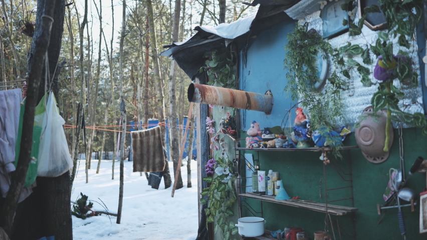 The homeless come out of their hut in the winter in the woods.