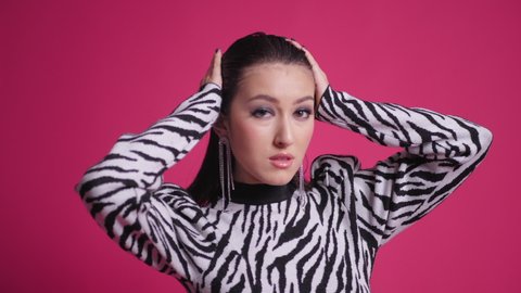 sexy young fashion model Asian woman is standing in a zebra striped dress in the studio on red background. protection of wild animals in nature from hunters