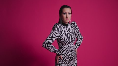 sexy young fashion model Asian woman is standing in a zebra striped dress in the studio on red background. protection of wild animals in nature from hunters