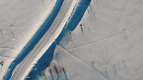 Aerial top down 4k view of winter tractor-cleared road. Road among snow.