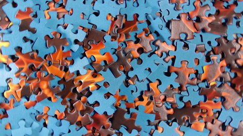 Background of Colored Puzzle Pieces that Rotating Counterclockwise - Top View. Texture of Incomplete Red and Blue Jigsaw Puzzle - Left Rotation