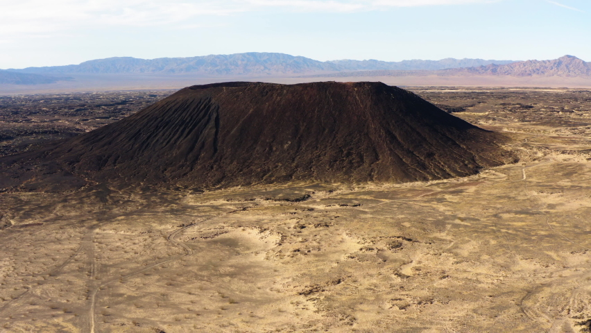 Aerial cinematic landscape view of Amboy crater National Natural Landmark in southern California, drone fly close to dormant cone volcano during a sunny day