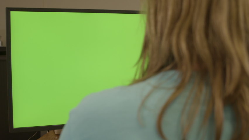 Dolly of woman sitting behing a green computer screen