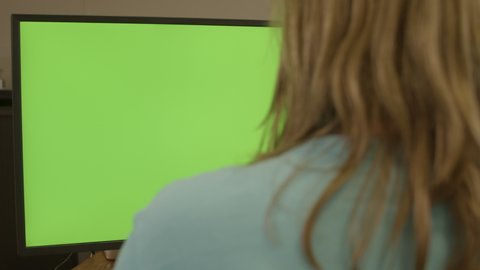Dolly of woman sitting behing a green computer screen