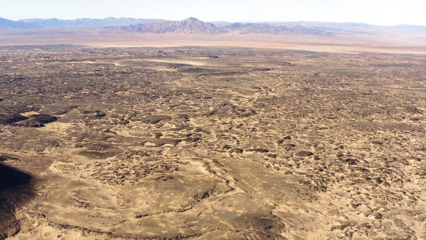 Aerial view of remote landscape in Mojave Desert of southern California revealing Amboy Crater is a dormant cinder cone volcano during a sunny day