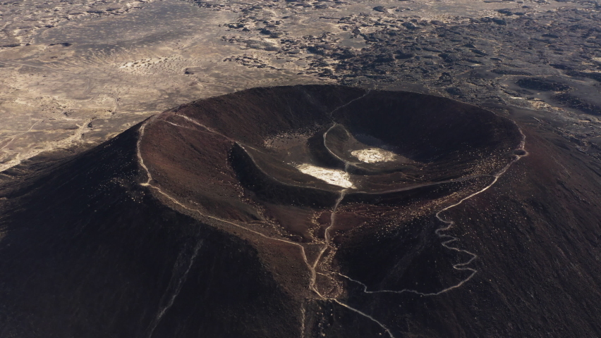 Cinematic aerial view of Amboy Crater dormant cinder cone volcano in the eastern Mojave Desert of southern California, Route 66 travel destination for adventurer trekkers