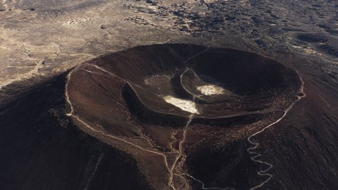 Cinematic aerial view of Amboy Crater dormant cinder cone volcano in the eastern Mojave Desert of southern California, Route 66 travel destination for adventurer trekkers
