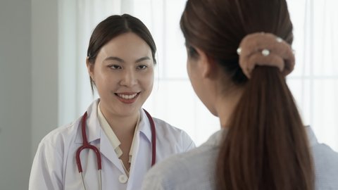 4k 50fps, A long-haired Asian female doctor stands inquiring about the patient's condition and talking with a smiling face.