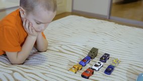 Five years old boy playing model cars on the sofa at home. 4k video 