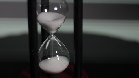 Wooden hourglass. Realistic glass hourglass. 3D stopwatch on a brown stand. Old-fashioned countdown timer. The falling, flowing particles are measured in a transparent flask.