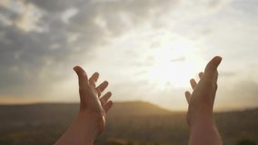 Close-up view 4k video footage of 2 female beautiful hands isolated on sunny sunset sky background. Woman making gentle movements of praying to God in soft golden magic sunlight. Woman's hands