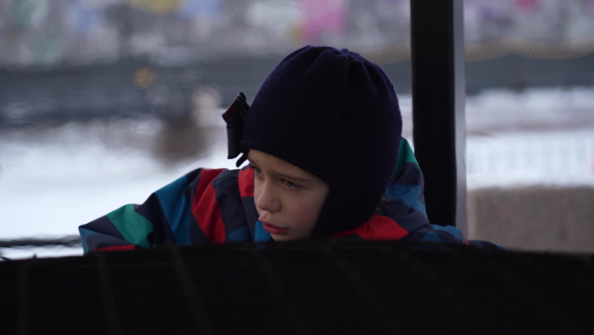 Little frozen girl is warming herself by big fire in city park at winter