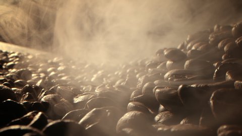 Macro shot roasting coffee beans, filmed in a dark key the smoke emanating from the roasting of coffee beans. Fragrant coffee beans are roasted smoke comes from coffee beans.