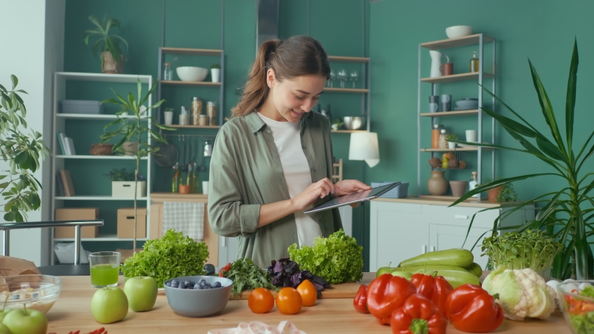 Young Woman Makes a Diet Plan of Correct Nutrition Using a Tablet in the Kitchen, Using a Calorie Counter in a Weight Loss App. Nutrition and Dietetics. Healthy Food and Technology Concept. Royalty-Free Stock Footage #1087522619