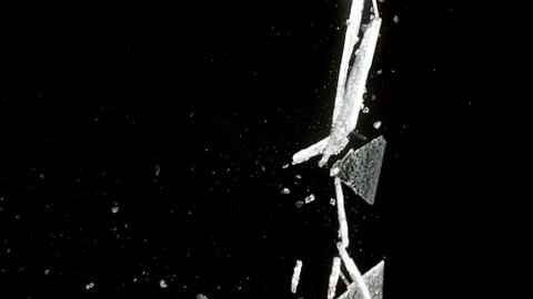 Fragments of broken glass fly in different directions on a black background.
