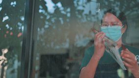 female cafe owner holds up a sign to show she is open for business.Asian woman with mask business owner opening store. - Powered by Shutterstock - Get 15% off with code: PIKWIZARD15