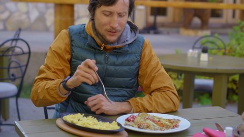 A man tourist visits northern Montenegro. He eats famous northern dish called kacamak made of boiled potato, corn, cheese, and milk cream