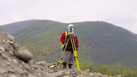 Professional Surveyor Worker Uses Theodolite Equipment To Measure Quarry Area. Industrial Surveyor Theodolite Equipment Operated By Geology Specialist. Modern Mining Surveyor Theodolite Equipment