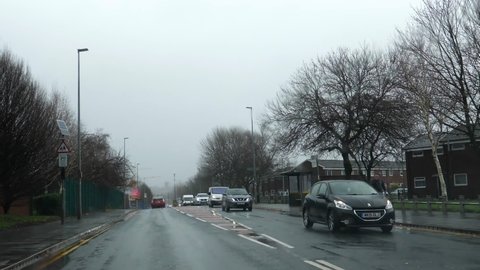 SALFORD, ENGLAND, UNITED KINGDOM - CIRCA FEBRUARY, 2022: Driving Broughton Road past Shell petrol or gas station in Greater Manchester in bad weather, car windscreen view.