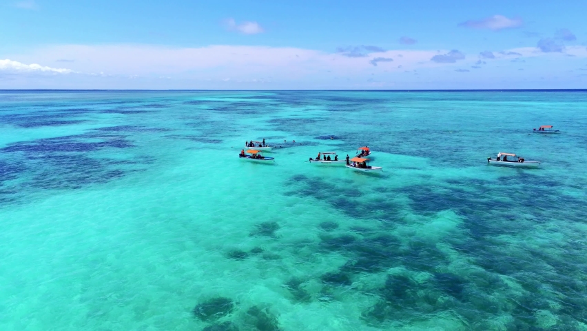Group of small african motorboats on the tropical Indian Ocean. Zanzibar with young people diving. drone 4k orbit shot Royalty-Free Stock Footage #1087540958