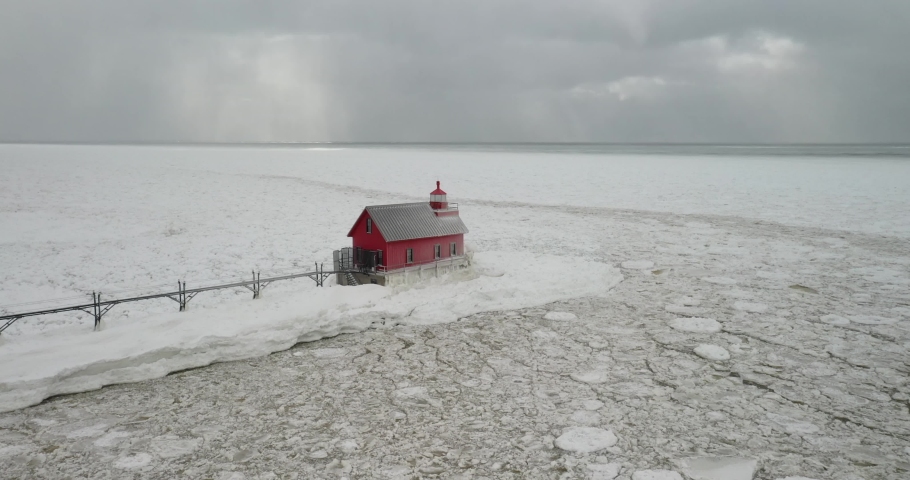Grand Haven, Michigan lighthouse in the winter at Lake Michigan with drone fly over.