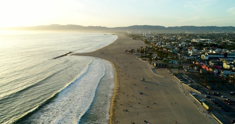Aerial shot moving along the coast of Venice Beach, CA at sunset.