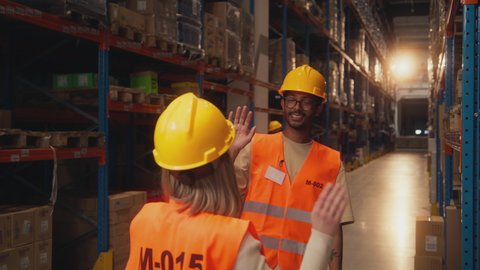 Two workers giving high five to each other for a job well done in stockroom.