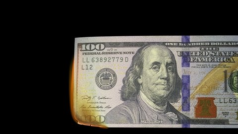 Close up footage of a 100 dollar banknote burning on a black background.