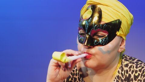 A Jewish woman in a headdress and a carnival mask commands when to make noise in the synagogue on Purim during the reading of the scroll by blowing the whistle