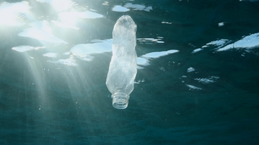Plastic pollution, discarded plastic bottle slowly drifting under surface of the water in sun rays on dawn. plastic bottle in blue water. Plastic garbage environmental pollution problem in Ocean | Shutterstock HD Video #1087548131