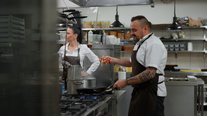 Professional chef preparing meal, flambing indoors in restaurant kitchen.