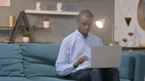 African Man Talking on Video Call on Laptop on Sofa