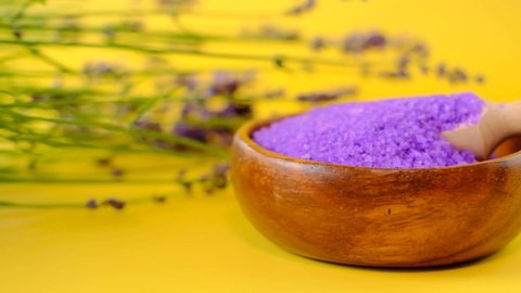 Lavender salt.Aromatherapy and spa with lavender extract.Purple sea salt and lavender flowers on a bright yellow background. Body cosmetics with lavender scent. High quality 4k footage