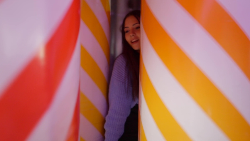 Valencia funfair attraction - a beautiful young woman walking through rolling inflated soft striped balloons