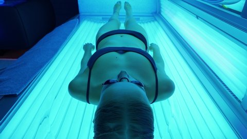 Sun treatments in a horizontal solarium, female takes a sun bath in a solarium, blue light.