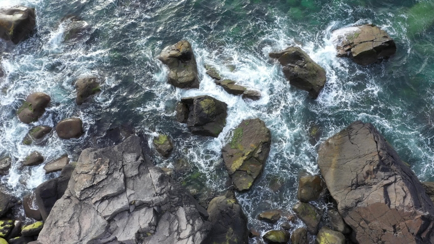 Top down View on the Rocky Beach with Splashing Sea Waves.Aerial view of a transparent blue sea with beautiful waves at the sunny day . | Shutterstock HD Video #1087560428