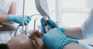 A male patient lies in a dental chair while a doctor examines his teeth using a dental camera. Close-up of the patient's face, side view. Video in 4k, red komodo