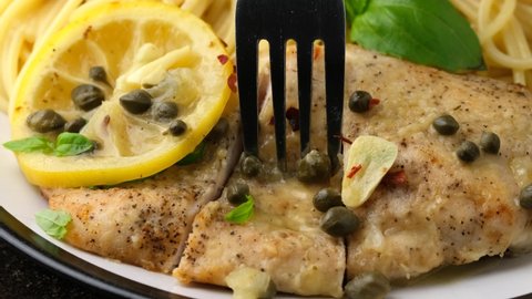 Eating Chicken Piccata with capers, white wine sauce and spaghetti