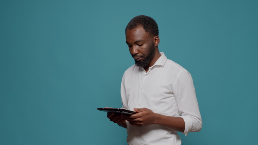 Company worker browsing internet on digital tablet in studio, working on internet website to plan successful executive data. Millennial man using electronic gadget with touchscreen for work.