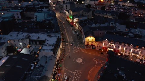 High angle view of traffic in streets of night city. Forwards tracking of car driving through evening town. Killarney, Ireland